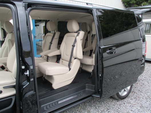 The left hand interior of a black four seater Mercedes V Class luxury mini van